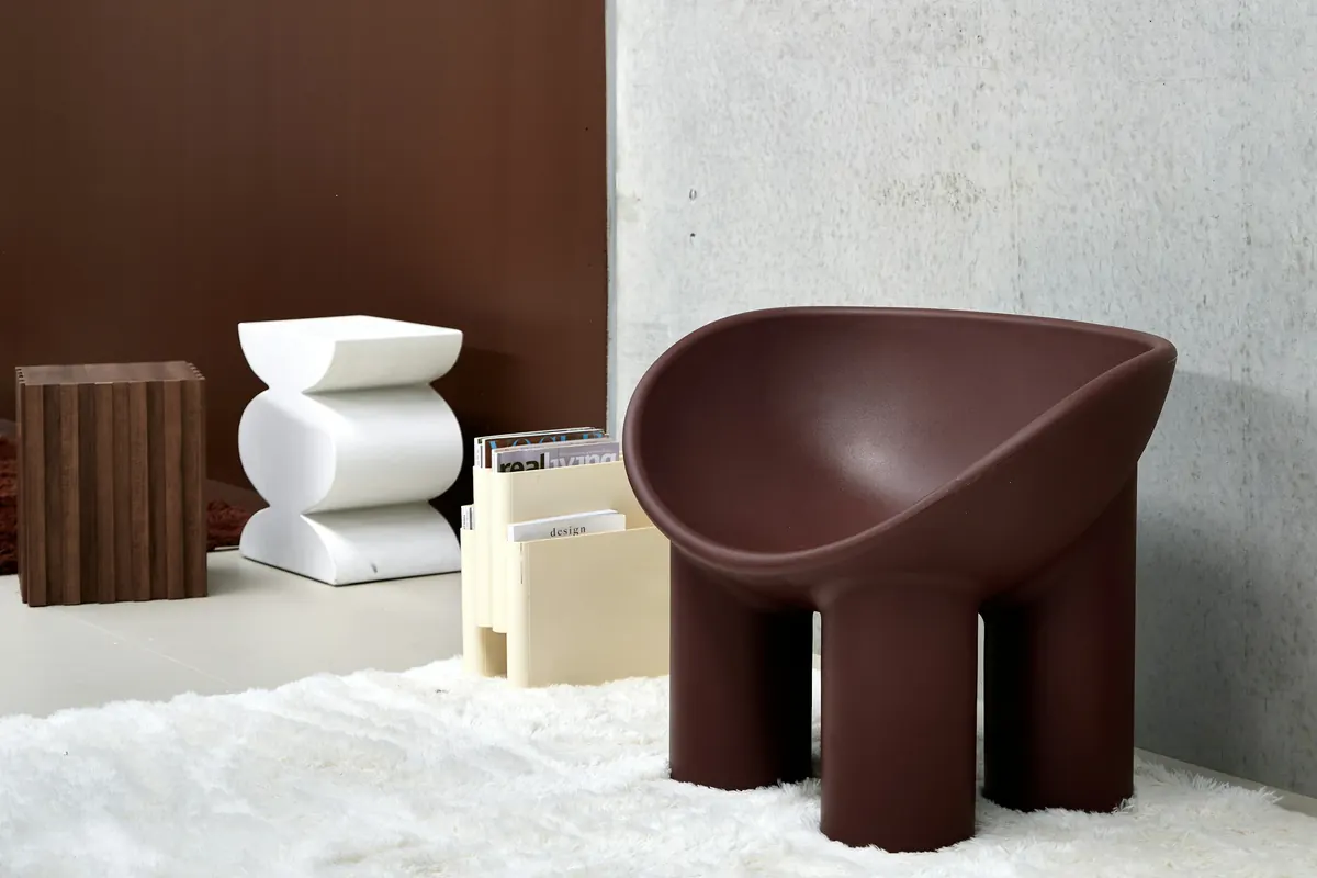 A sculptural burgundy chair against a chocolate-brown wall