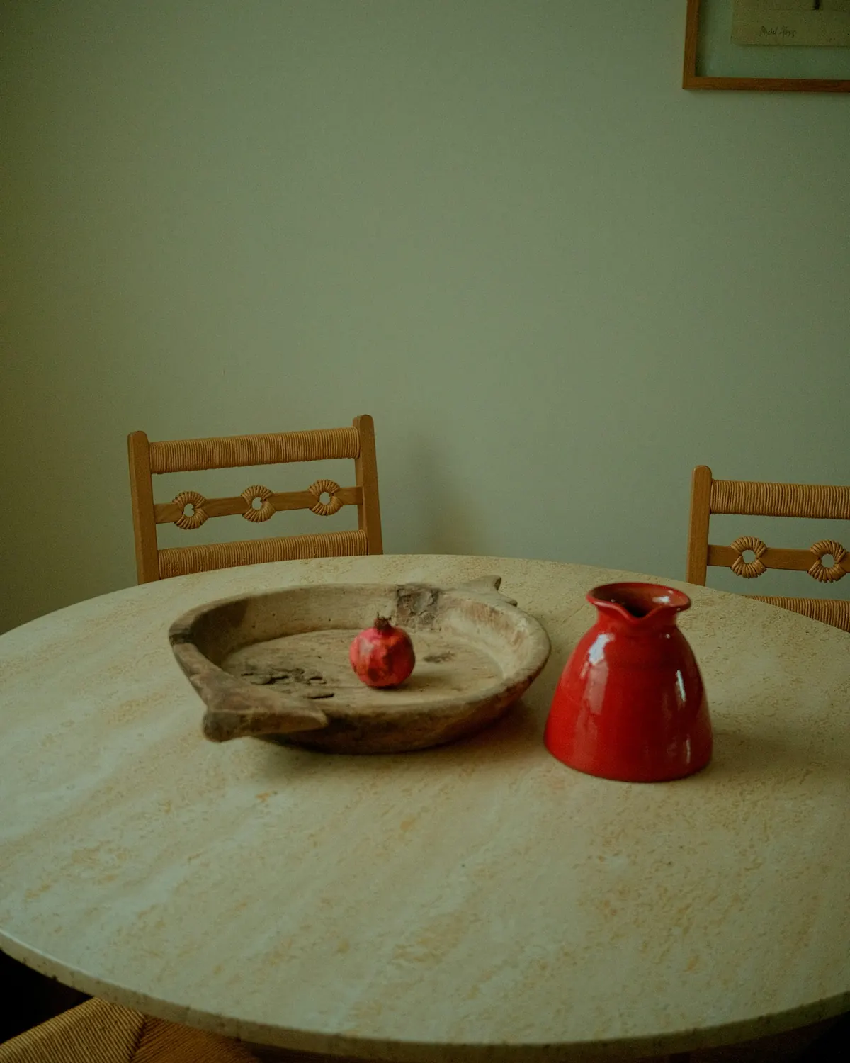 A round table with a wooden bowl and a red jug