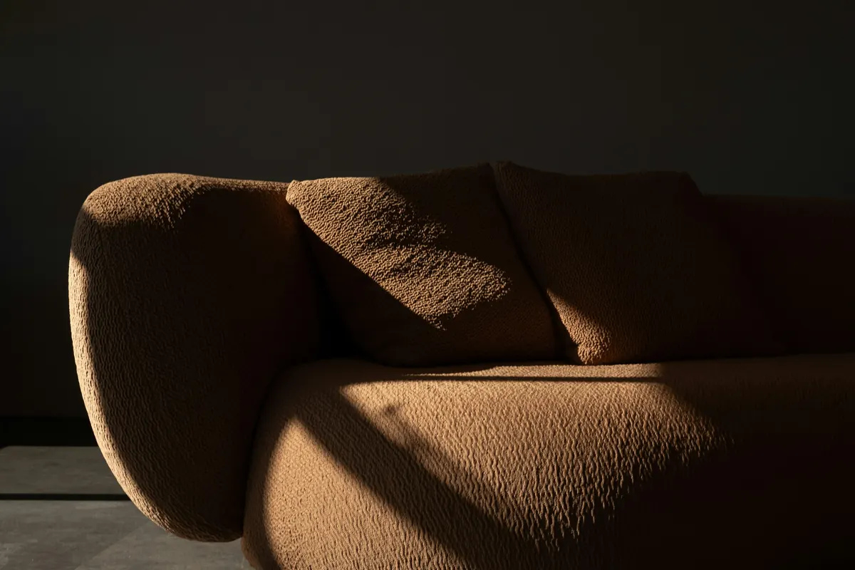 A rounded bouclé sofa catching soft light
