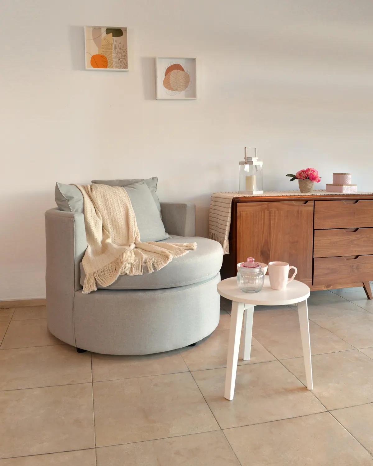 A rounded armchair with a loosely draped throw beside a round table