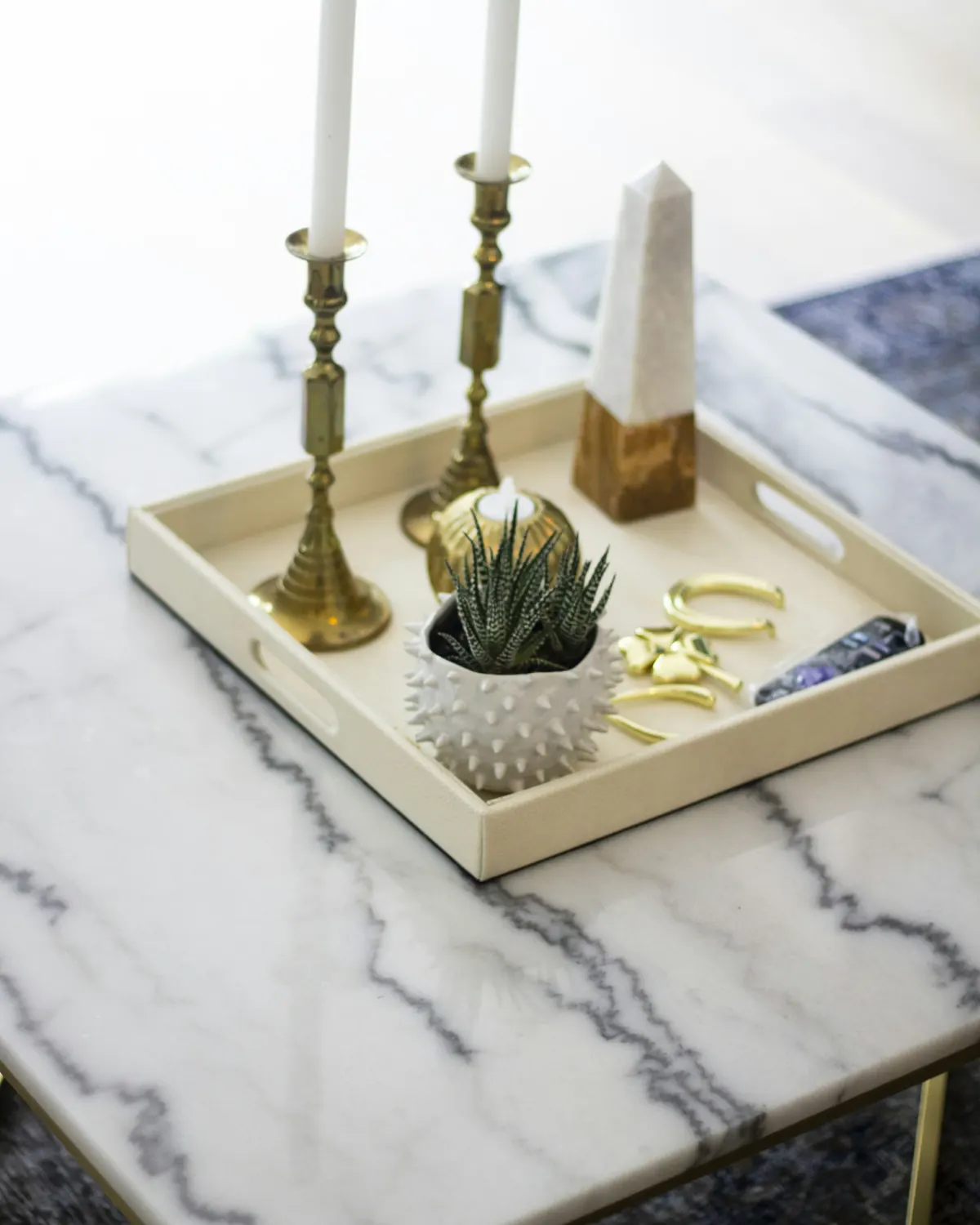 Brass candlesticks on a tray atop a veined marble table