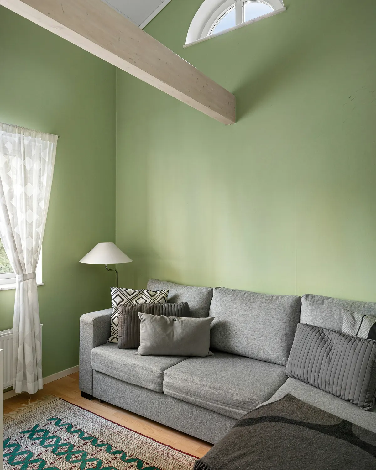 A living room with sage-green walls and ceiling