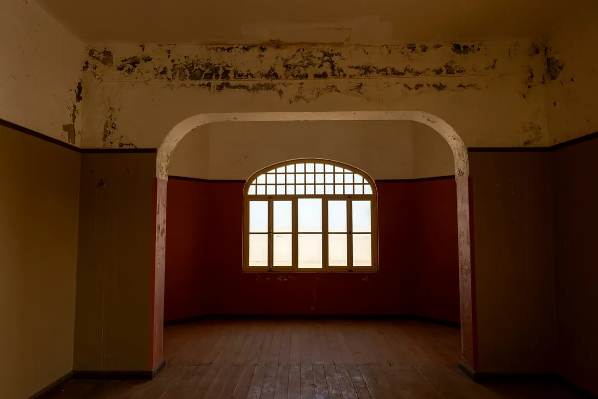 An empty room with an arched window and wooden floor