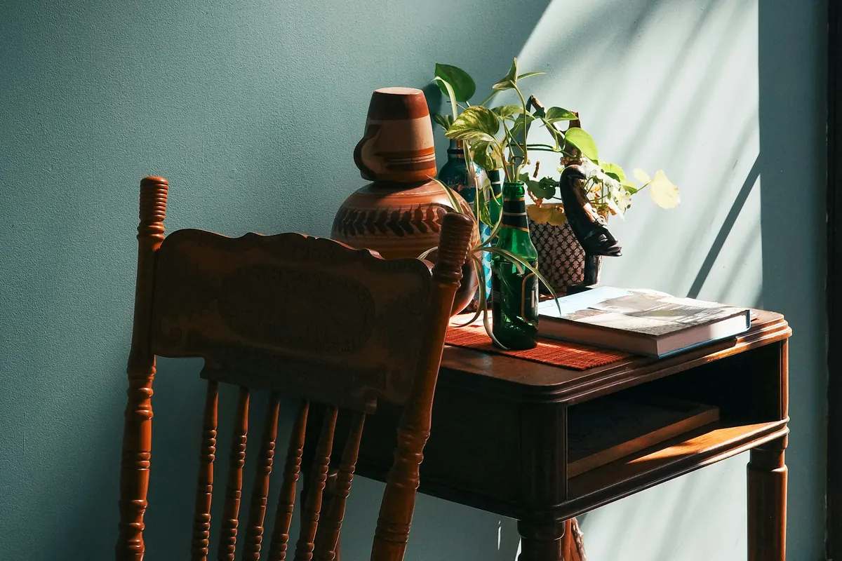 A lived-in corner with a wooden desk and chair against a green wall