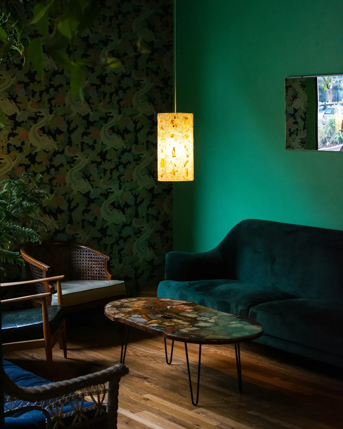 A deep green room lit by a hanging lamp at night