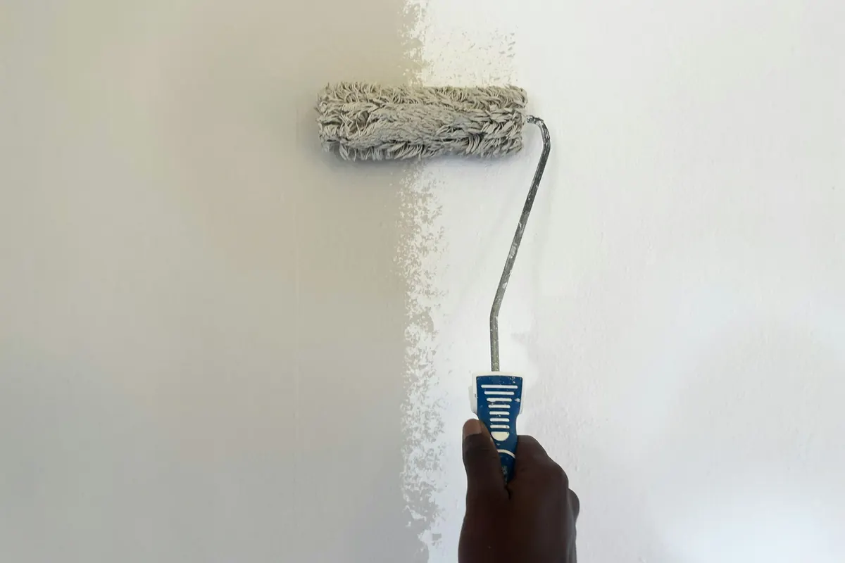 A hand rolling paint onto a wall
