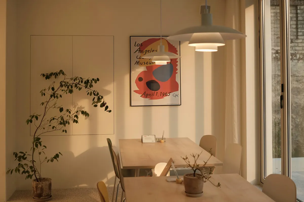 A dining table beneath a pendant lamp in warm light