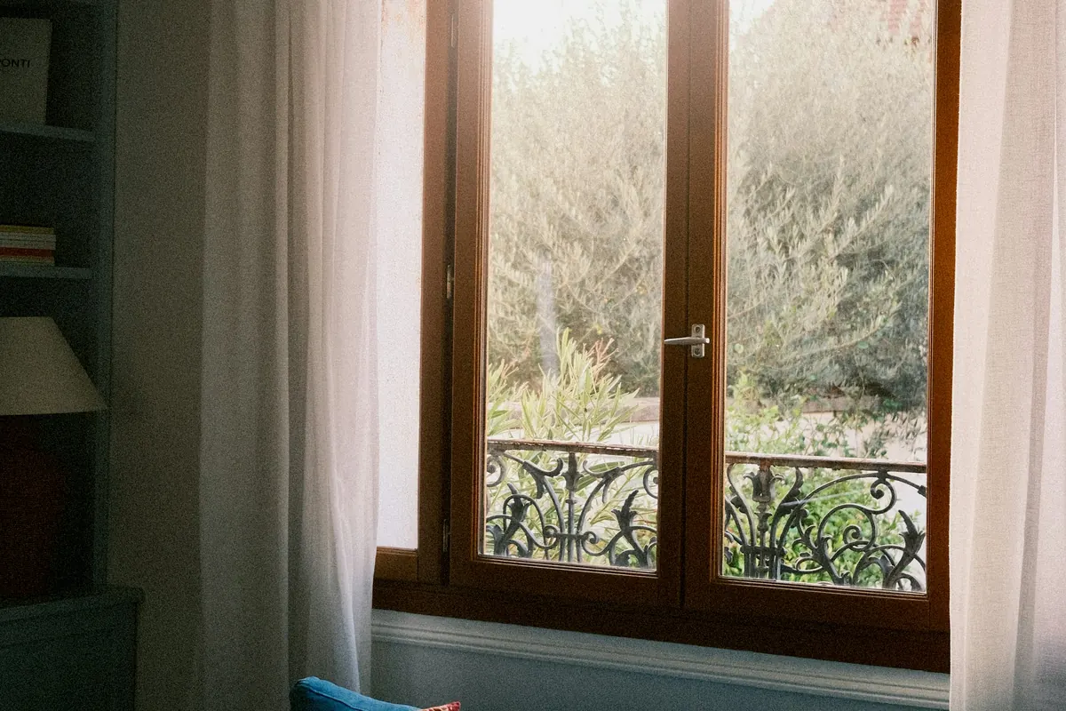 Morning light through a tall window with sheer curtains