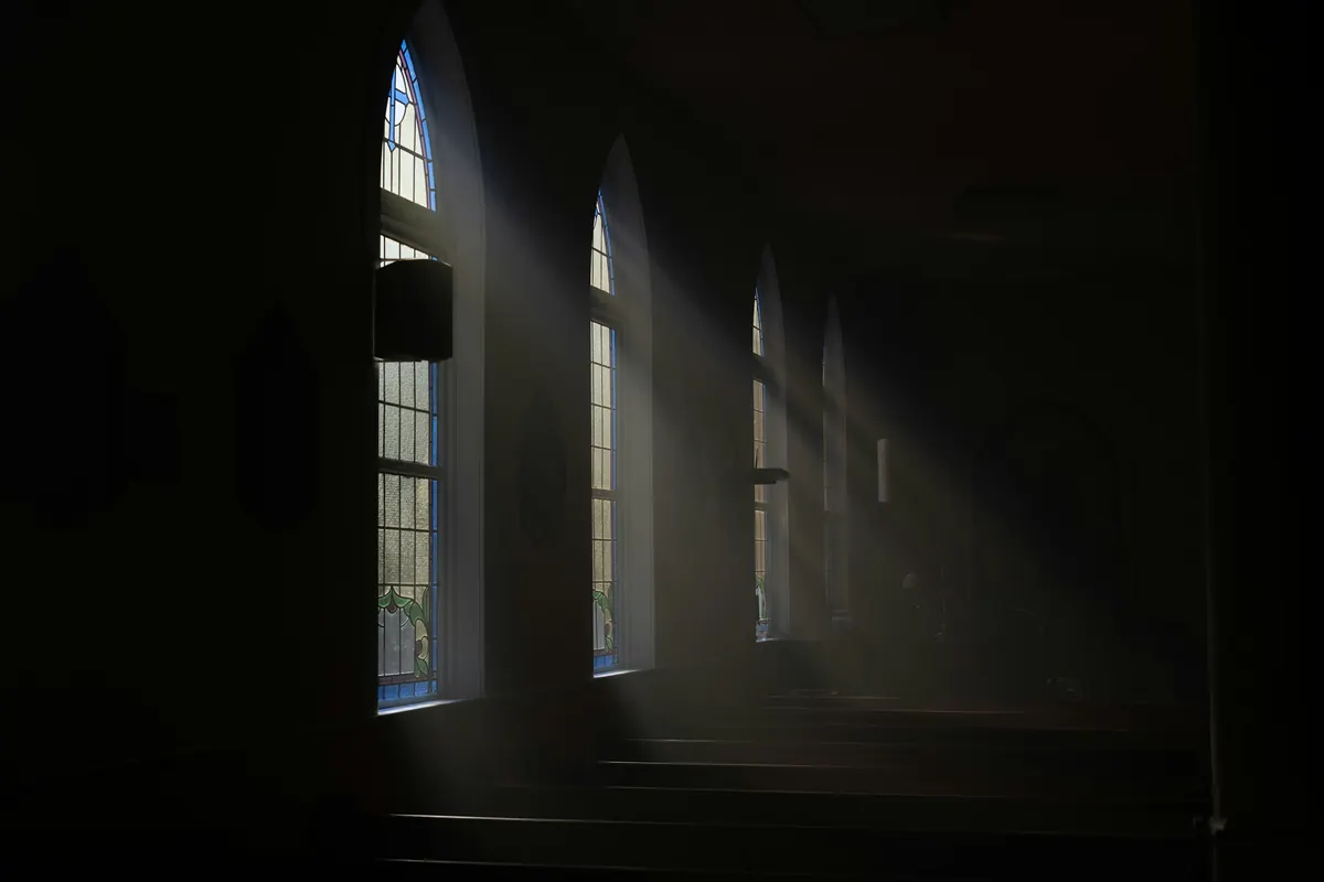 A quiet, dim passage with soft light from arched windows