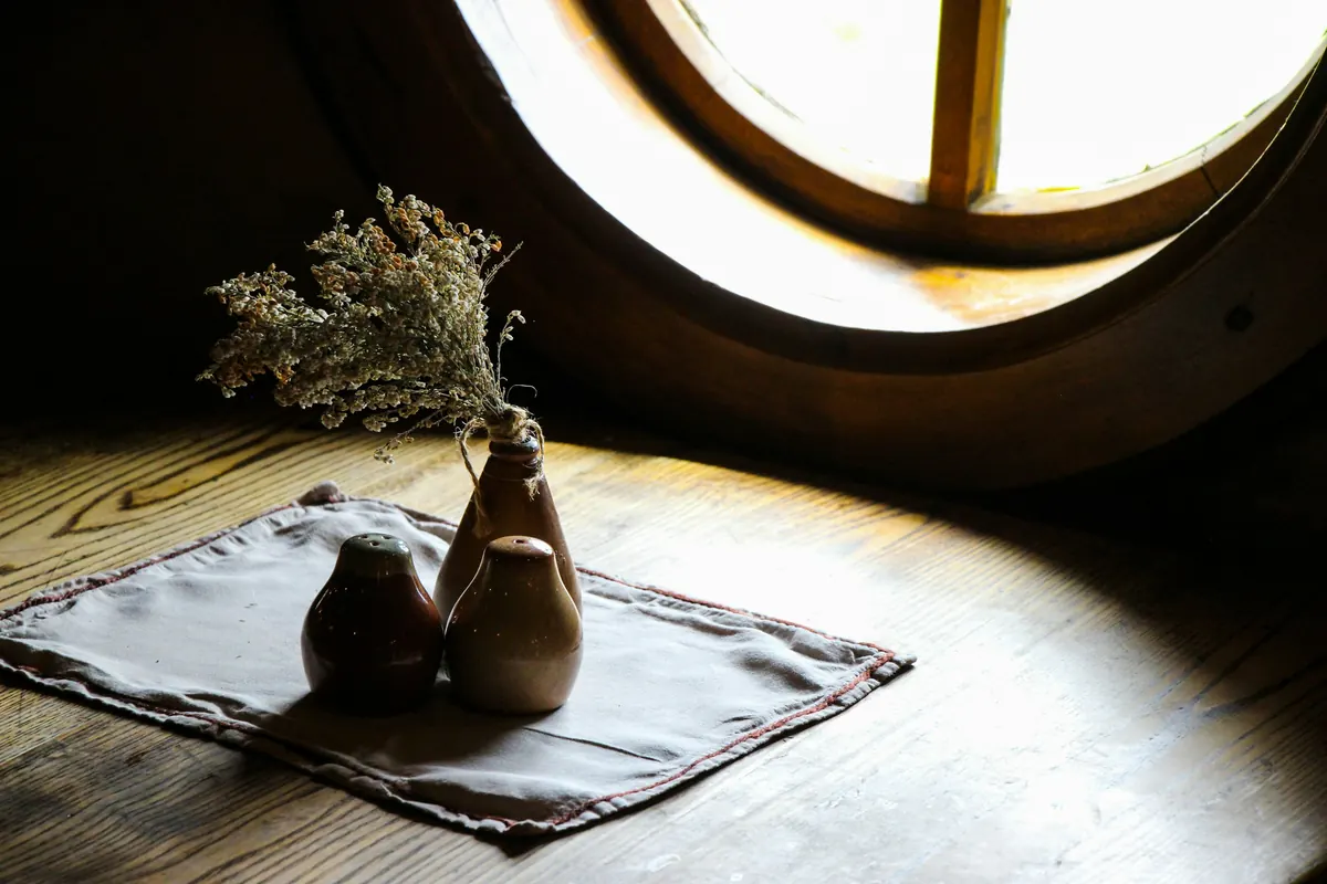 Ceramic vases on a linen cloth lit by a round window