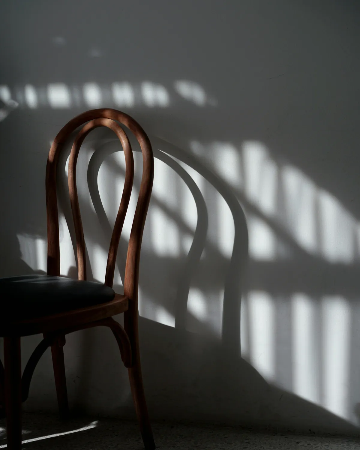 Morning sunlight falling across a wooden chair and the wall behind it