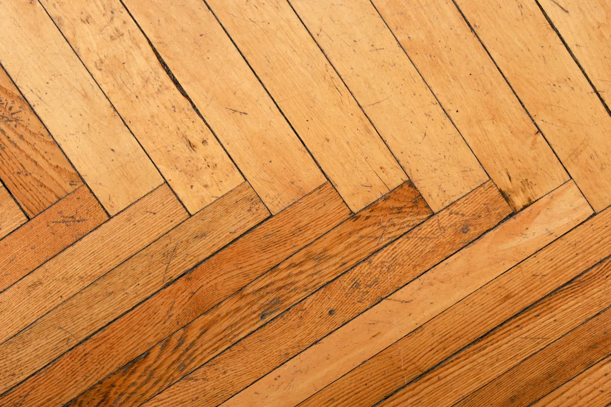 Close-up of worn herringbone parquet flooring in warm daylight