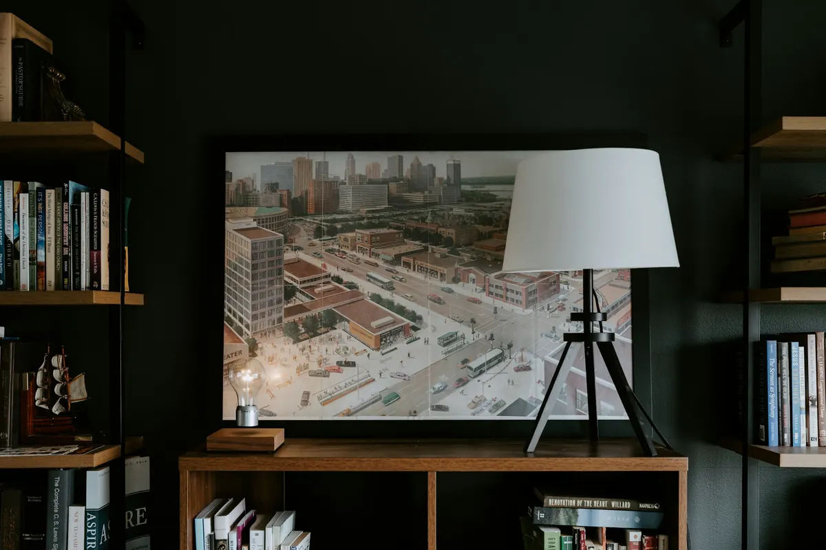 A lamp glowing beside bookshelves in the evening