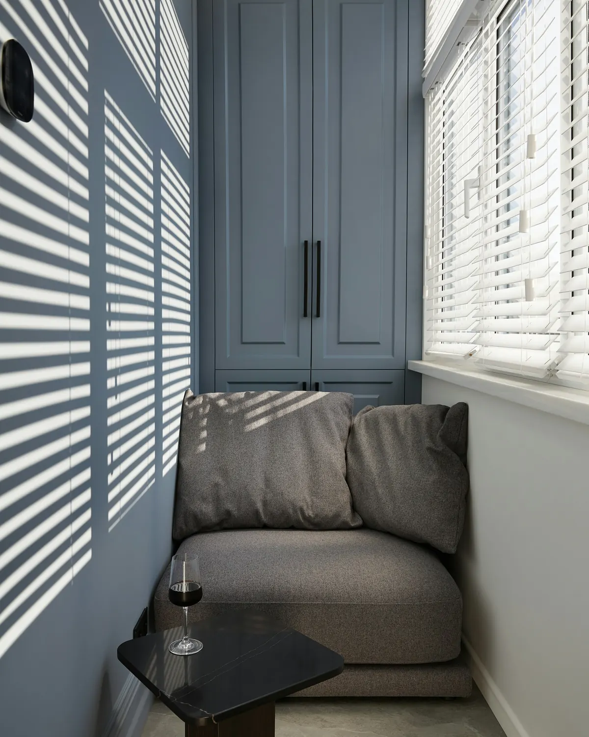 A tiny window nook with a soft seat and striped light