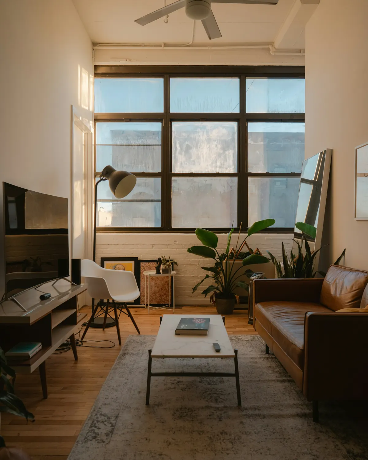A compact living room with a leather sofa and a clear walkway to the window