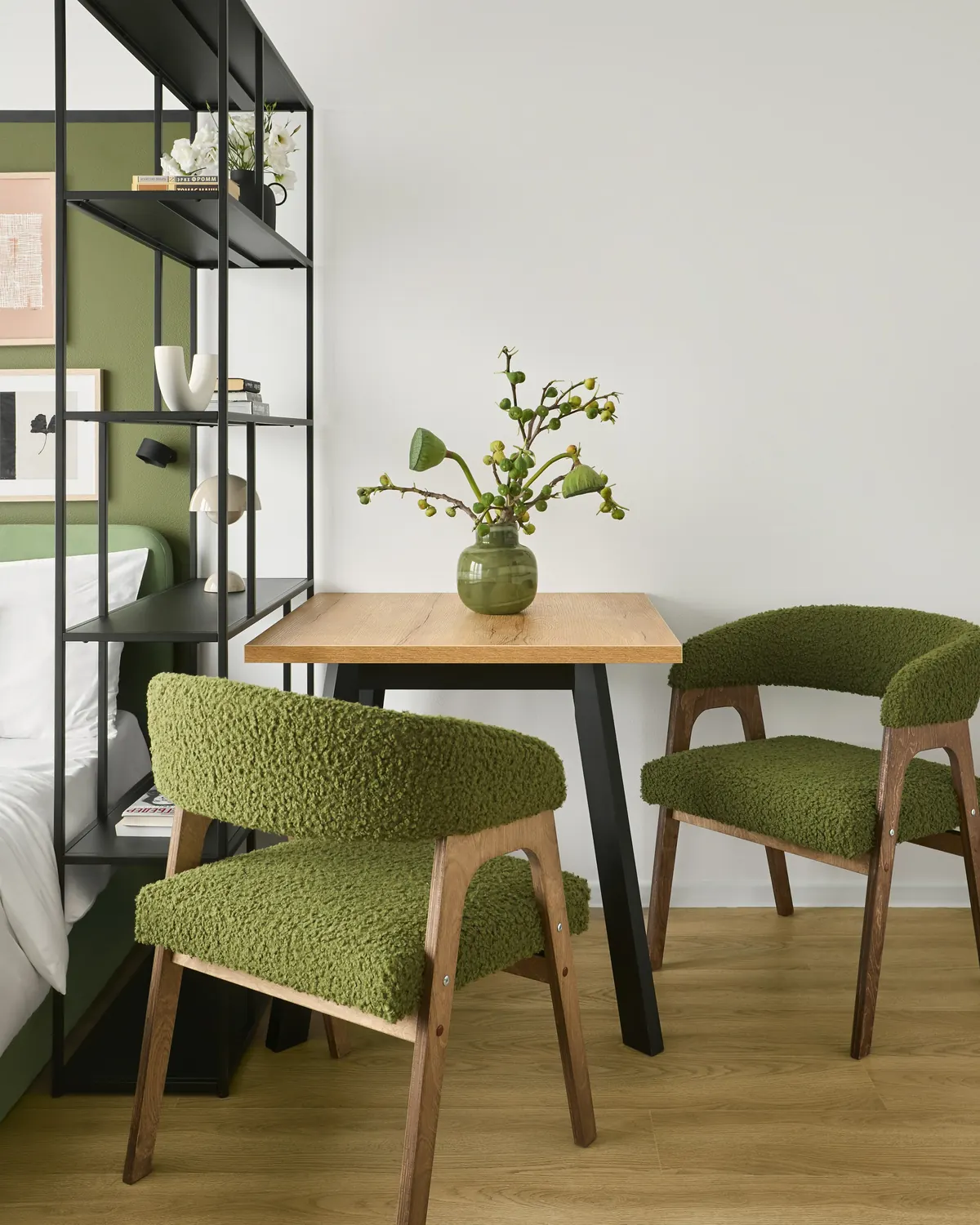 A small table with two green chairs beside an open shelf