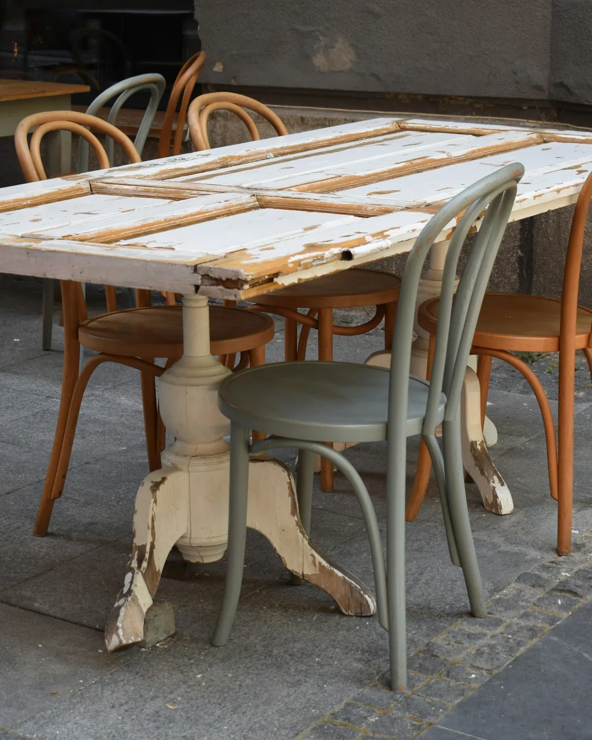 Mismatched wooden chairs around a weathered table