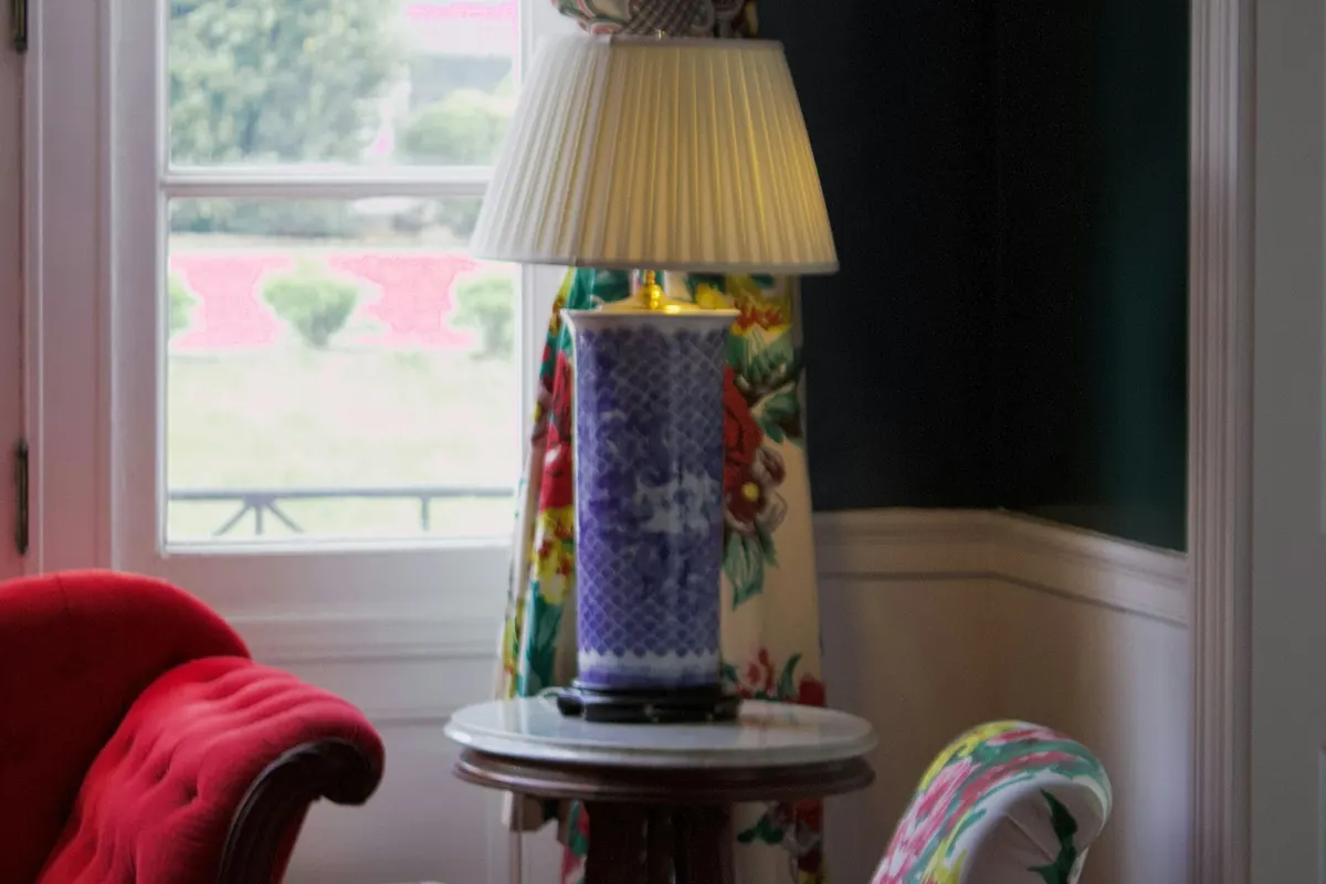 A vintage lamp and a red armchair by a window