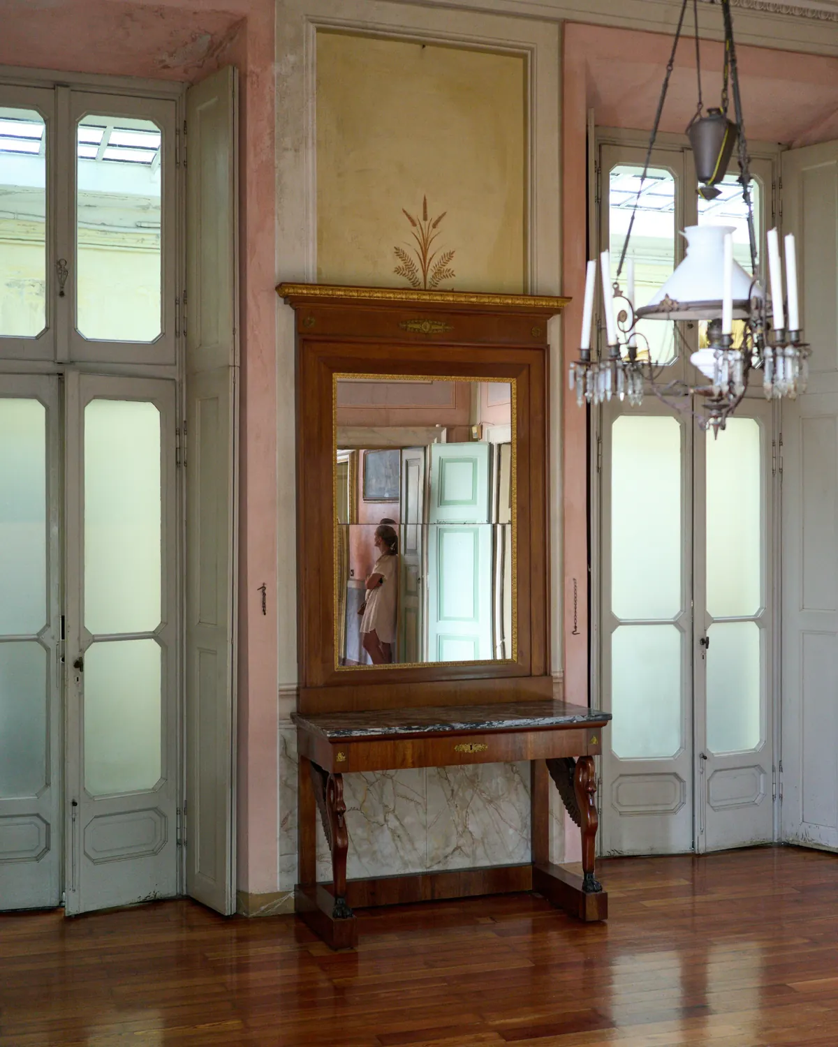 An antique wooden mirror above a narrow console in a hallway