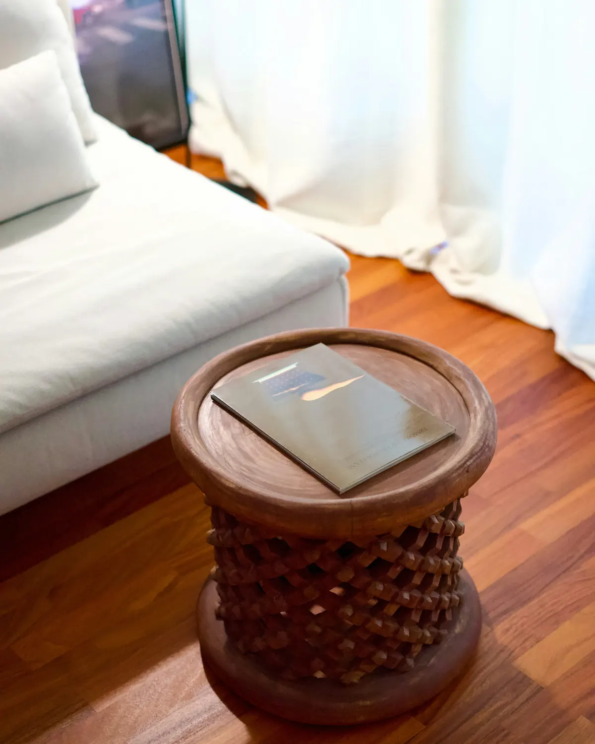 A carved wooden side table beside a modern sofa