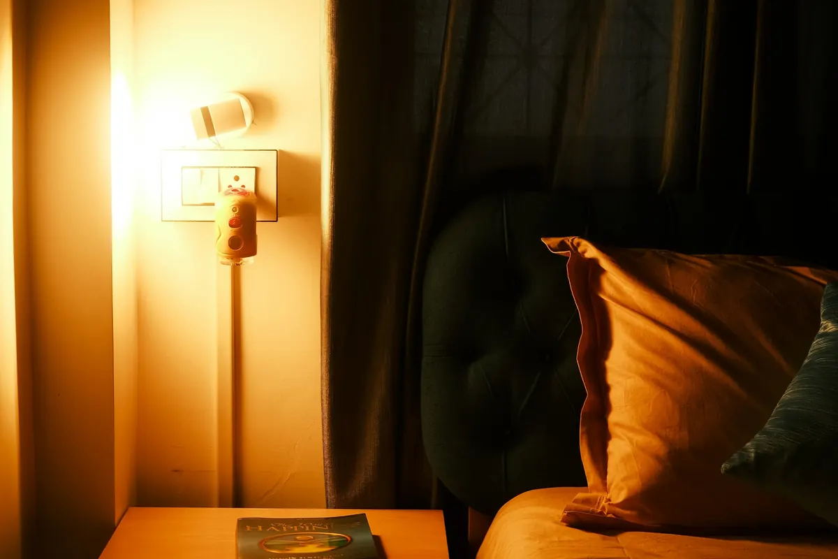 A warm lamp glowing beside a bed at night
