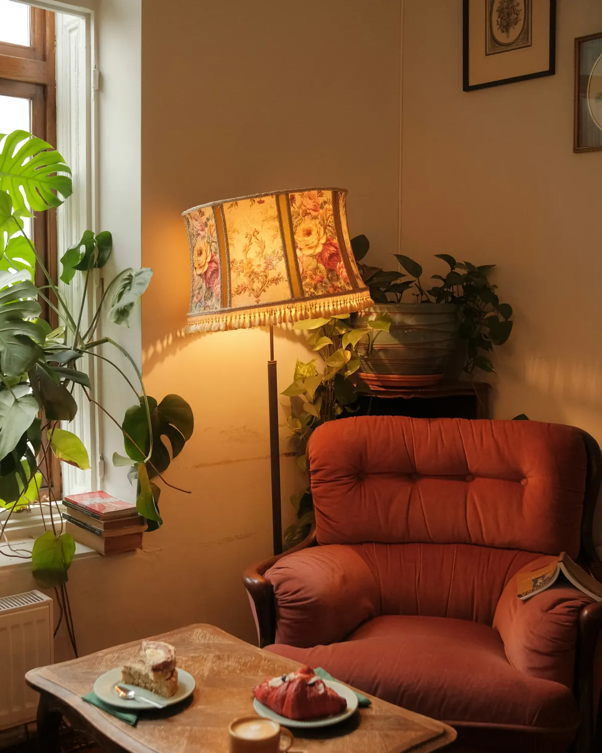 A floor lamp glowing beside a terracotta armchair