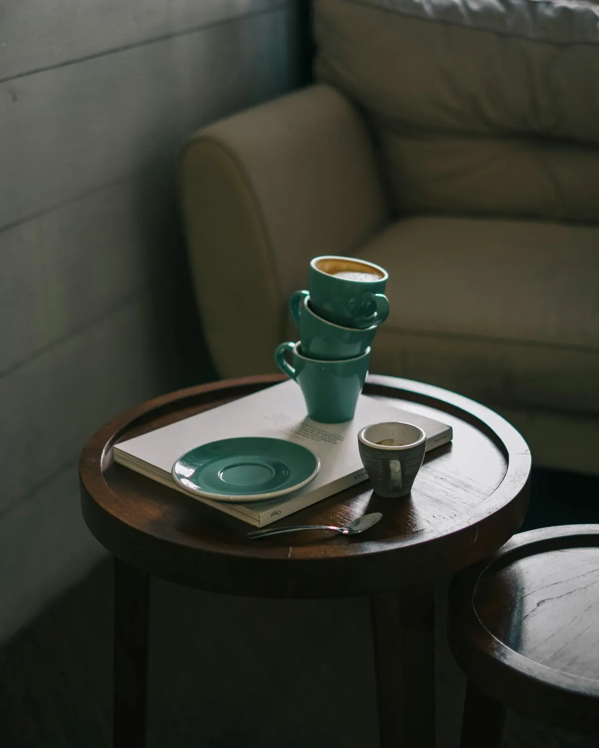 A small wooden side table with stacked cups beside an armchair