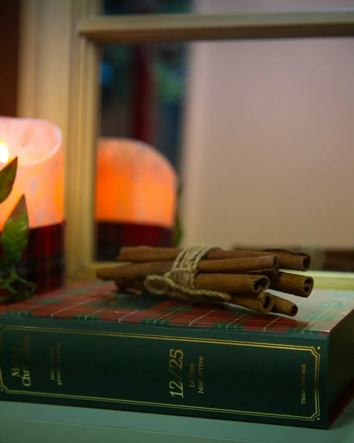An old book with cinnamon sticks beside candlelight