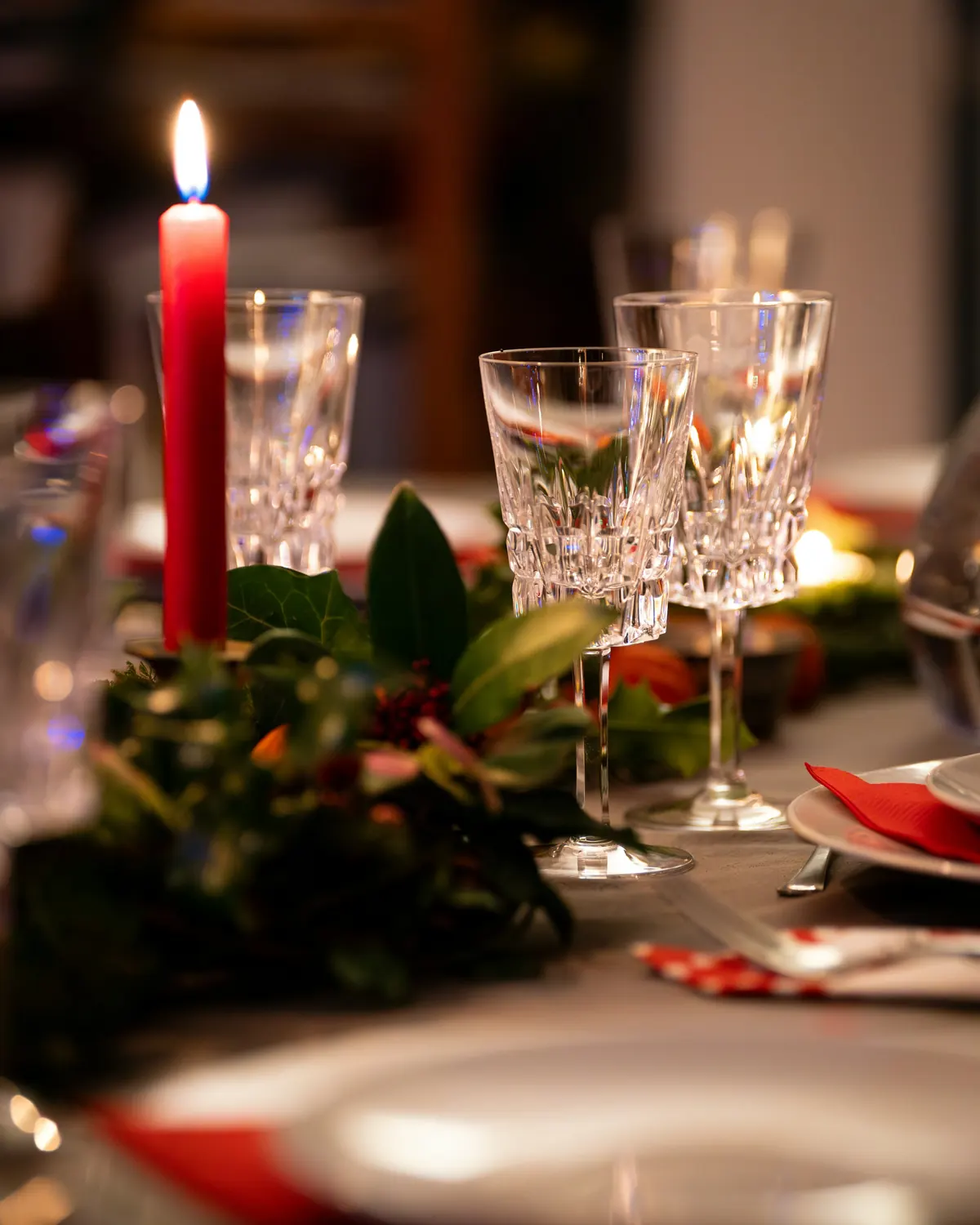 Cut-glass goblets and a red candle on a festive table