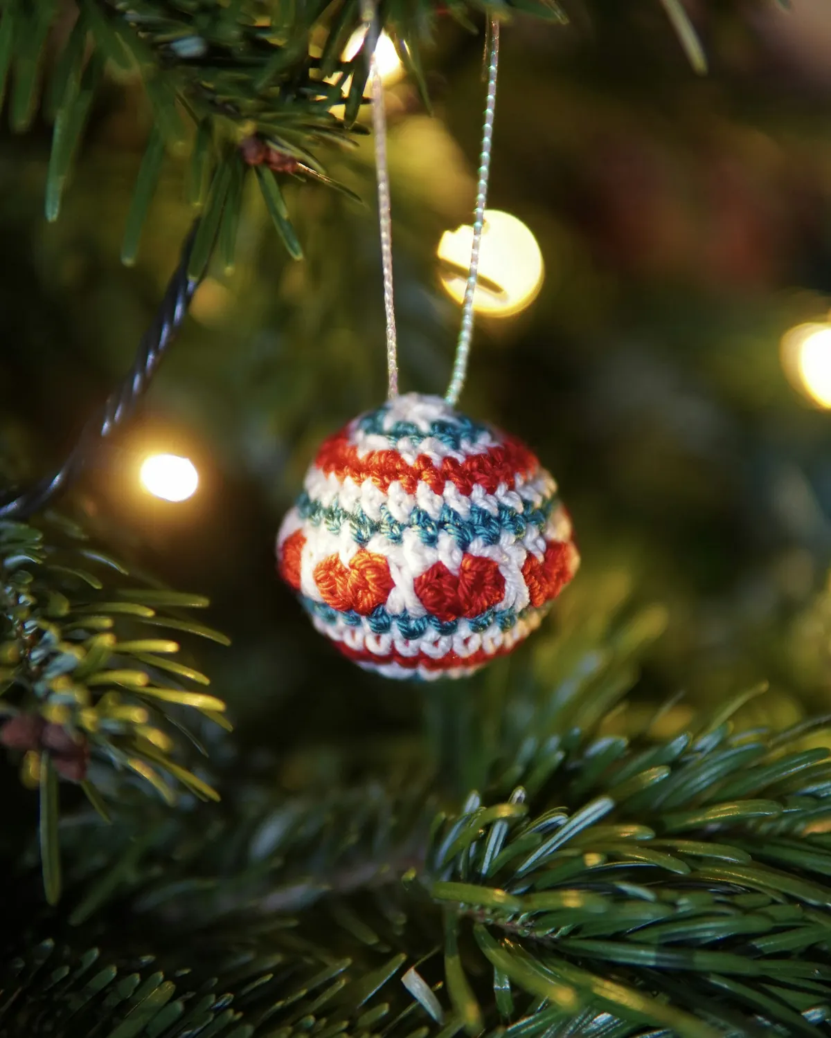 Handmade crochet ornament hanging among evergreen branches